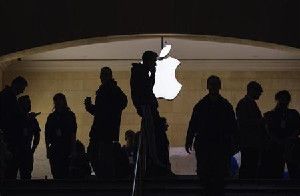 A man talks on his telephone as customers walk through an Apple store in Grand Central Terminal in New York, March 15, 2013.