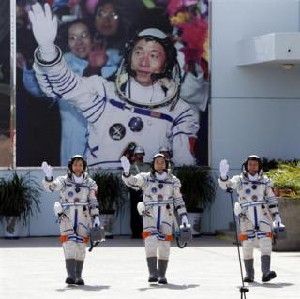 Chinese astronauts Jing Haipeng (C), Liu Wang (R) and Liu Yang, China's first female astronaut, wave in front of a picture of the first astronaut Yang Liwei during a departure ceremony at Jiuquan Satellite Launch Center, Gansu province, June 16, 2012.