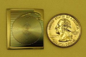 A photograph of the spiral chip-based optical resonator developed at Caltech, shown next to a quarter to provide scale. (Credit: Hansuek Lee/Caltech)