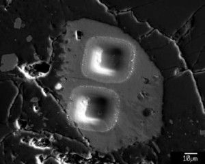 This shows secondary electron image of pits left by ion microprobe analyses of a heterogeneous apatite grain in Apollo sample 14321, 1047. Water has now been detected in apatite in many different lunar rock types.