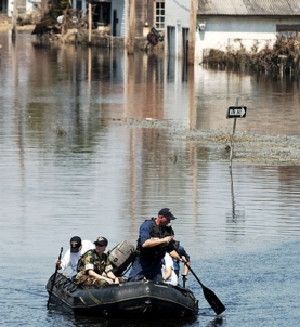 Sailors search a flooded New Orleans neighborhood after fatal levee failure. Inadequate and aging infrastructure could not protect Louisiana from Hurricane Katrina, 2005.