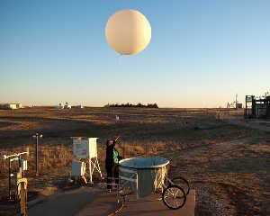 A technician at a Department of Energy site in Oklahoma launching a weather balloon to help scientists analyze clouds.