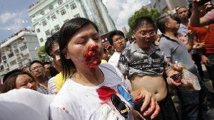 A bloodied woman is helped by demonstrators after clashes with police in a protest against an industrial waste pipeline in Qidong, Jiangsu province, on July 28. The Chinese government devotes enormous resources to suppressing dissent, but opposition to government policies is increasingly common.