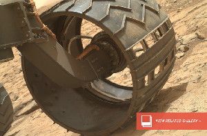 Curiosity’s dusty wheels. Dents are evident on the inner edge of the wheel’s skin and scratches cover the outer edge.