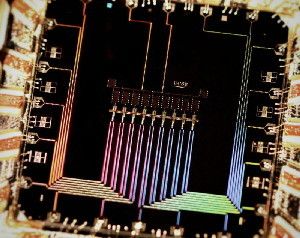A photograph of the nine qubit device. The device conists of nine superconducting 'Xmon' transmon in a row. Qubits interact with their nearest neighbors to detect and correct errors.