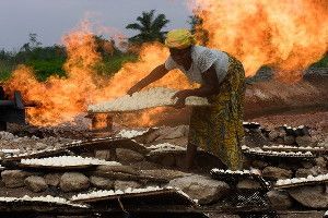 A woman dries cassava paste by a natural gas flare in Nigeria. Millions of people in Nigeria lack access to modern energy, even though the African nation is a major oil producer.